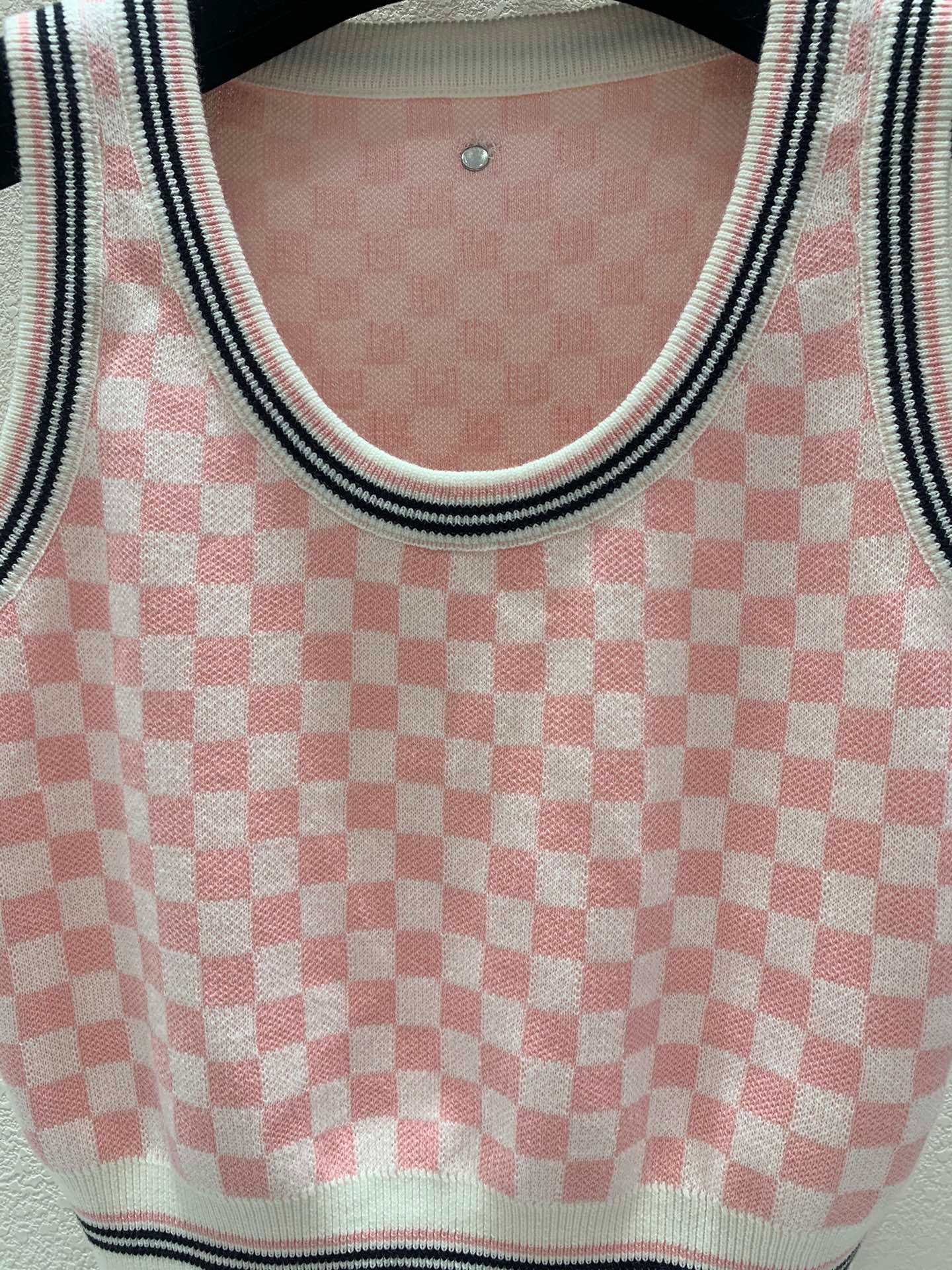 Pink and white checkerboard knit vest with a metal logo clasp on the back